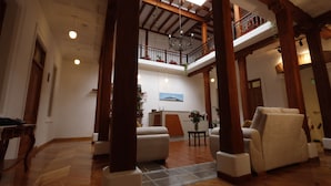 Un vestíbulo espacioso con techos altos, vigas de madera y un balcón con plantas en macetas.