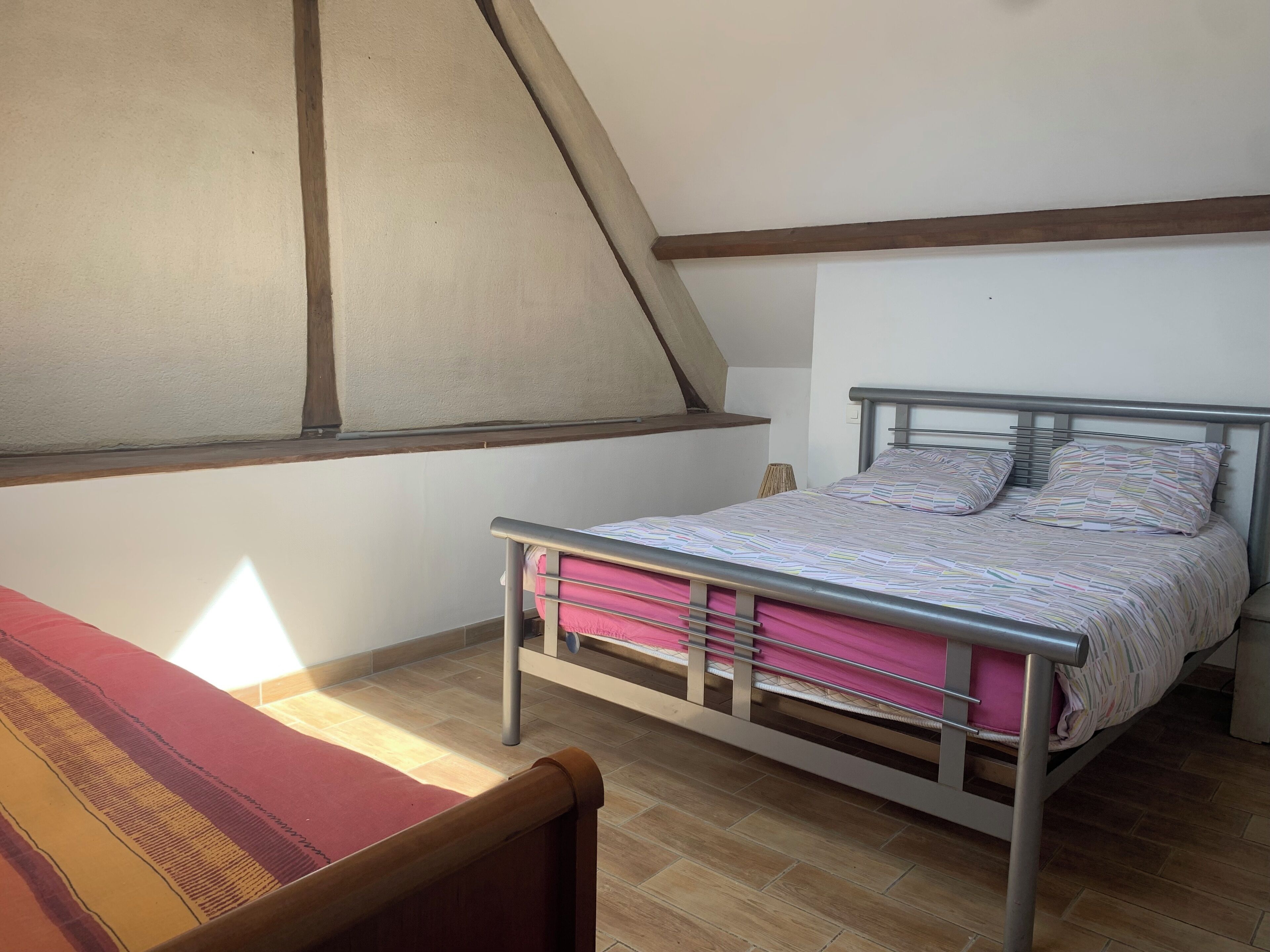 Un dormitorio con una cama, una ventana y suelo de madera.