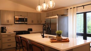 A modern kitchen with a large island, stainless steel appliances, and pendant lighting. - Spacious 5 BR House on the River (Indian River)