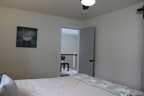 A bedroom with a bed, a painting on the wall, and a door leading to another room. - Spacious 5 BR House on the River (Indian River)