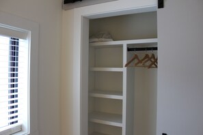 A walk-in closet with multiple shelves and a hanging rod. - Spacious 5 BR House on the River (Indian River)