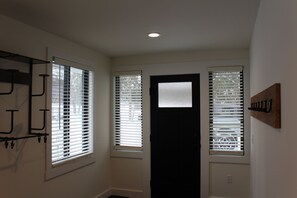 Un pasillo con dos ventanas, una puerta y un perchero.