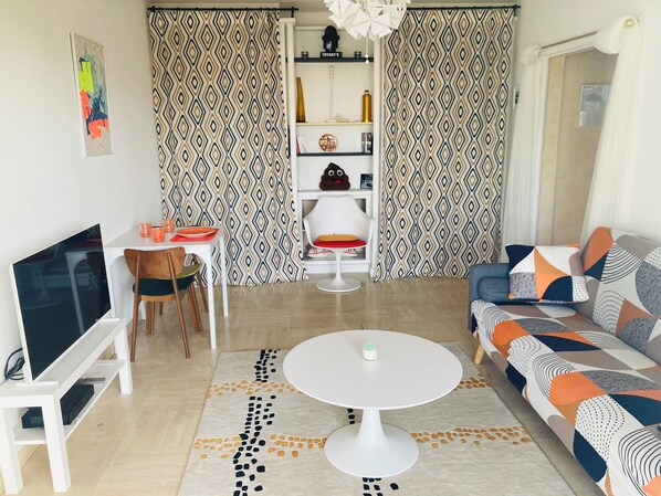 A modern living room with a TV, dining table, and sofa. - Vintage 70' apartment 45 m2 (Castelnau-le-Lez)