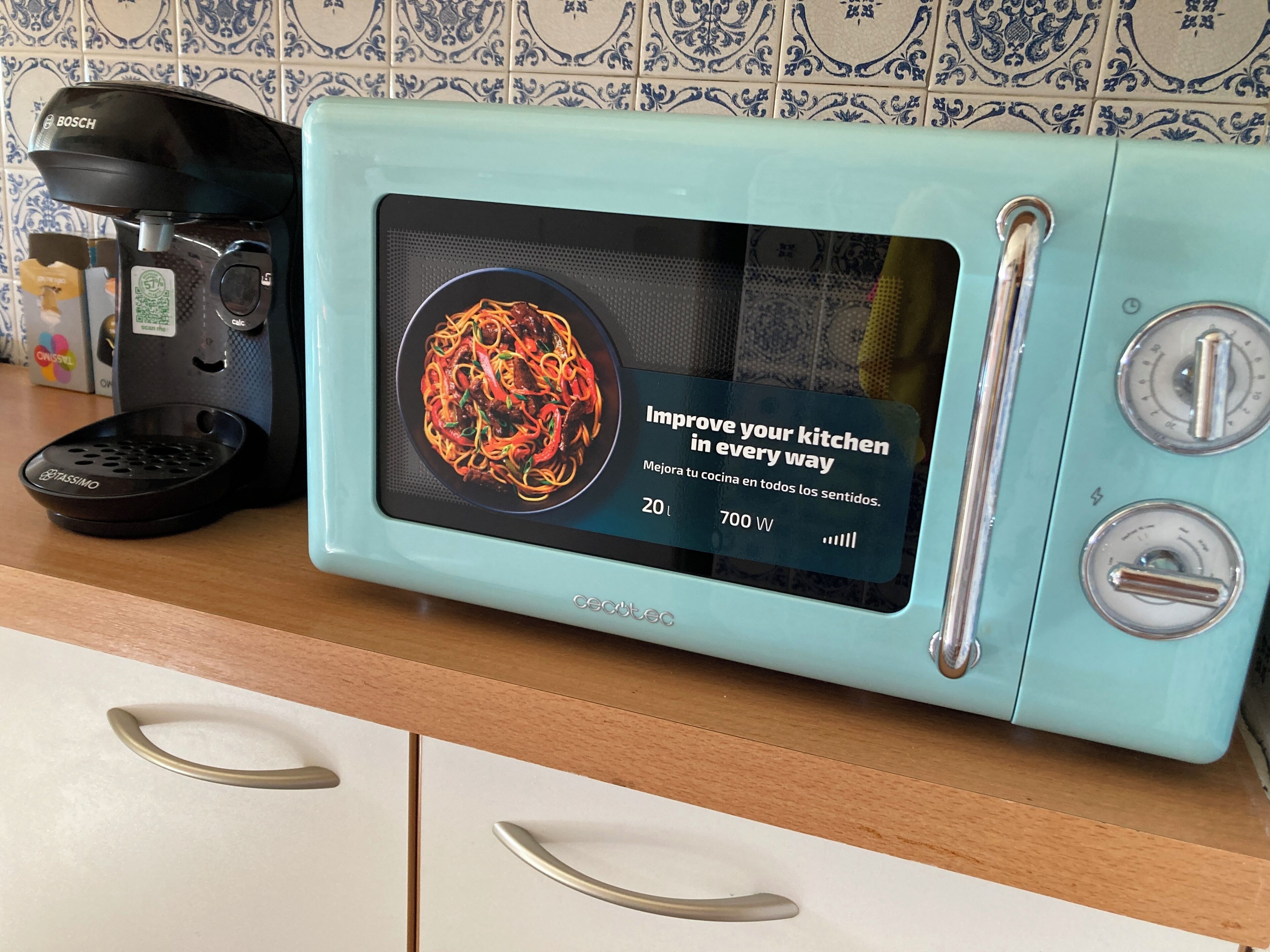 Un four à micro-ondes au design rétro doté d’un écran numérique, une machine à café et une balance de cuisine, le tout posé sur un plan de travail.