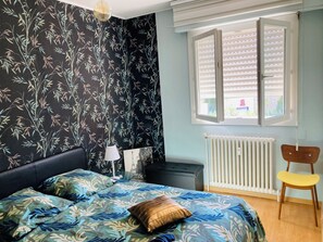 A bedroom with a bed, a radiator, a window with blinds, a chair, and a lamp. - Vintage 70' apartment 45 m2 (Castelnau-le-Lez)