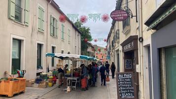 A narrow street with a market stall and a signboard listing wine and champagne.