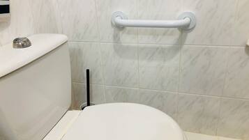 Et badeværelse med toilet, gelænder og væg beklædt med marmor.