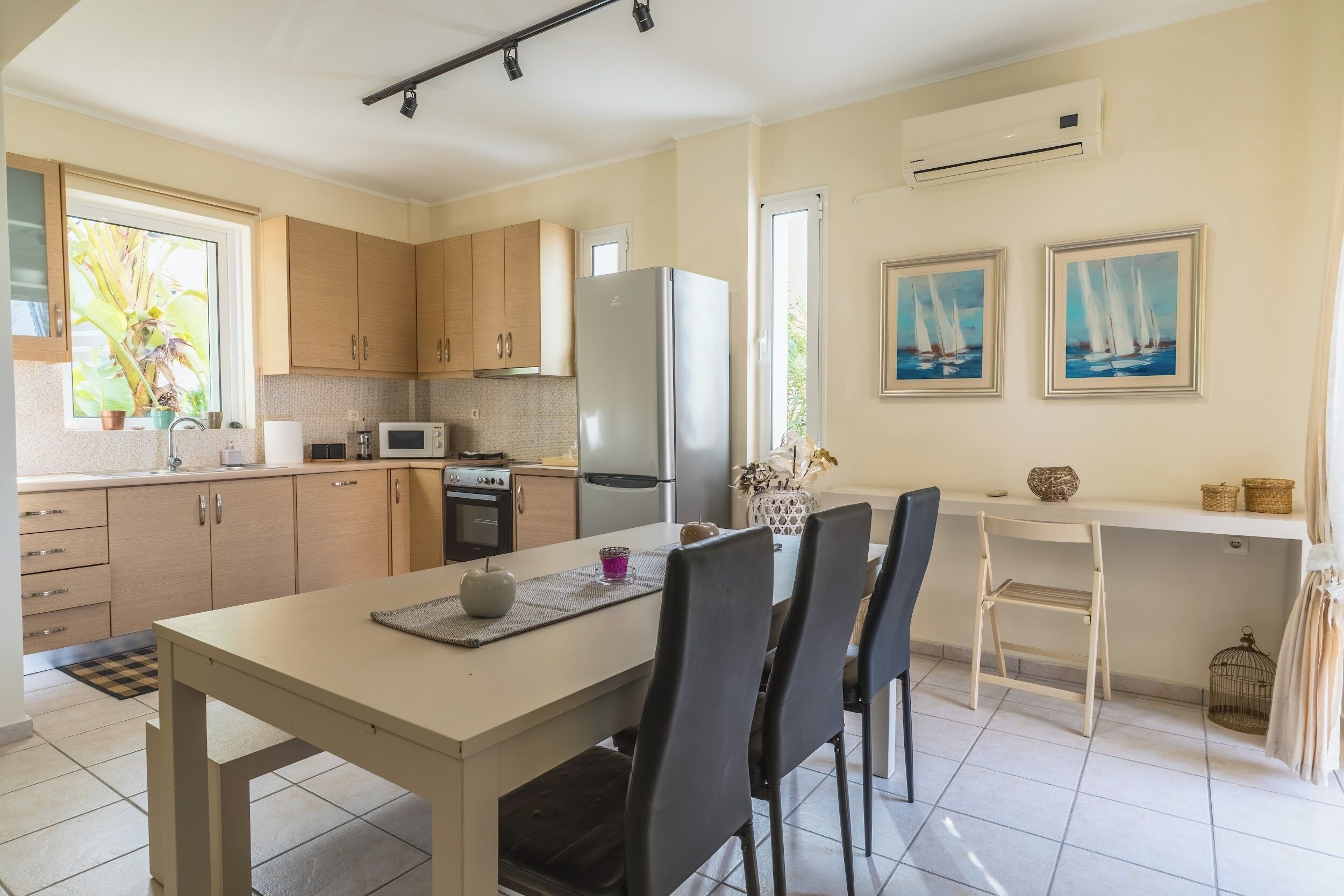 A modern kitchen with wooden cabinets, a stainless steel refrigerator, and a dining area with a table and chairs.