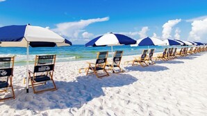 A beach with rows of sun loungers and umbrellas, a clear sky, and the ocean in the background. - Sunrise Serenity Summer House 1101A (Orange Beach)
