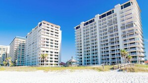 A beachfront hotel with multiple floors, balconies, and a clear view of the ocean. - Sunrise Serenity Summer House 1101A (Orange Beach)