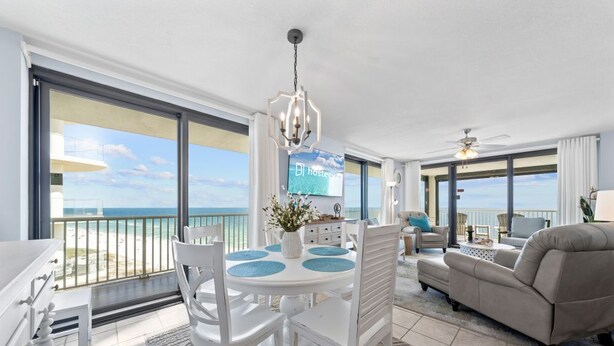 A modern living room with a dining area, large windows, and a view of the beach. - Sunrise Serenity Summer House 1101A (Orange Beach)