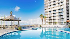 A swimming pool with lounge chairs and a gazebo, surrounded by a multi-story building with balconies. - Sunrise Serenity Summer House 1101A (Orange Beach)
