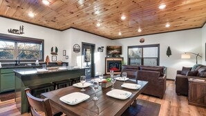 Un salón espacioso con techo de madera y una zona de comedor lista para una comida.