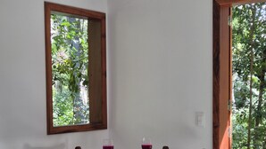 Une pièce avec un lit, une table où sont servis un repas et des boissons, et une fenêtre donnant sur un paysage verdoyant.
