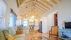 A spacious living area with a high ceiling, a kitchen in the background, and a television on a stand. - 3 Mins to Hull Bay | Dining | Quiet Retreat (St. Thomas)