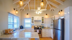 A spacious kitchen with a central island, white cabinetry, a stainless steel refrigerator, and pendant lighting. - 3 Mins to Hull Bay | Dining | Quiet Retreat (St. Thomas)