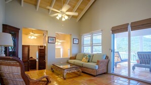 A spacious living room with a large window, a ceiling fan, and a sofa. - 3 Mins to Hull Bay | Dining | Quiet Retreat (St. Thomas)