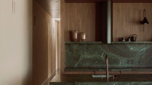 Une cuisine moderne avec des meubles en bois, un plan de travail en marbre vert et un évier en acier inoxydable.