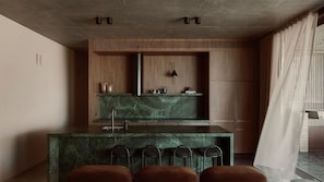 A modern kitchen with a central island, bar stools, and a pendant light.