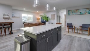 Una cocina moderna con una isla grande, armarios oscuros e iluminación colgante.