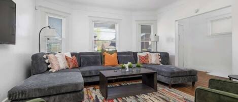 A modern living room with a sectional sofa, a coffee table, and a patterned rug.