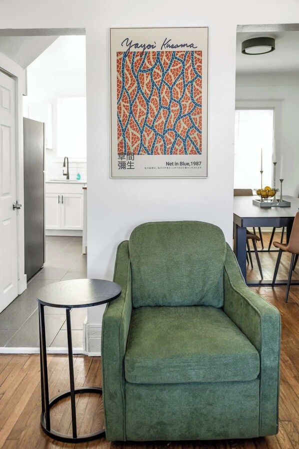 A green armchair in a modern living room with a framed artwork above it.