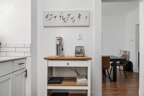 A kitchen with white cabinets, a coffee maker, a toaster, and a framed picture on the wall. - Spacious Home • 6 Beds + Free Parking • 5 min DT (Detroit)