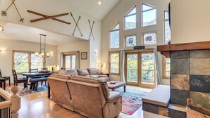 A spacious living room with a large beige sectional sofa, a fireplace, and a dining area with a wooden table and chairs. - Mtn-View Cabin w/ Private Hot Tub in Georgetown! (Georgetown)