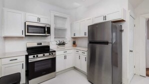 A modern kitchen with white cabinets, a stainless steel refrigerator, a microwave, and an oven. - Stylish & Comfortable 6BR • Sleeps 16 • Parking (Detroit)