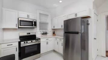 A modern kitchen with white cabinets, a stainless steel refrigerator, a microwave, and an oven.