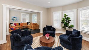 A living room with a sectional sofa, two armchairs, a coffee table, and a large plant. - Stylish & Comfortable 6BR • Sleeps 16 • Parking (Detroit)