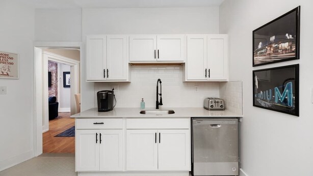 A modern kitchen with white cabinets, a stainless steel dishwasher, and a black coffee maker. - Stylish & Comfortable 6BR • Sleeps 16 • Parking (Detroit)