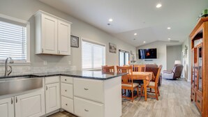 Una cocina moderna con armarios blancos, encimera de granito y comedor con mobiliario de madera.
