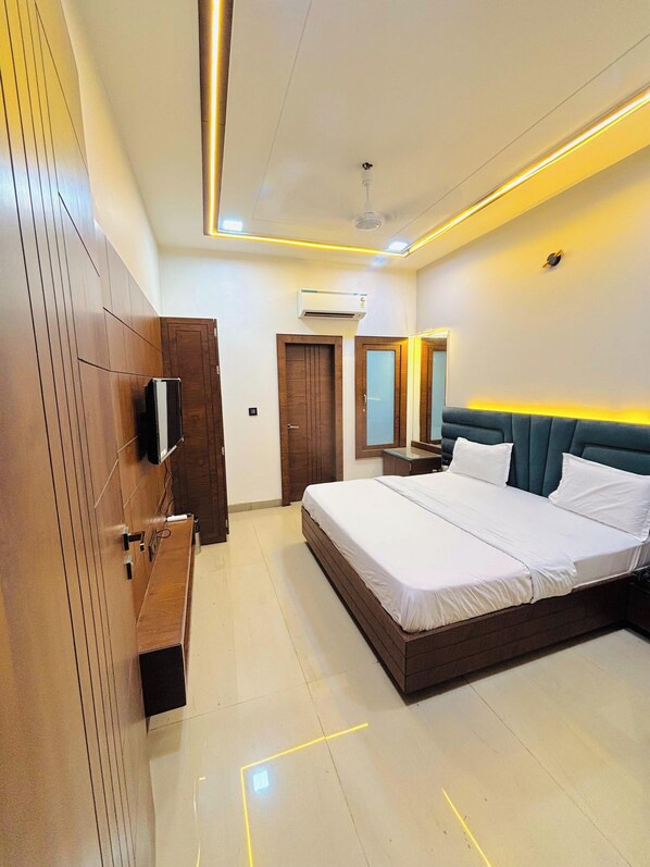 A modern bedroom with a large bed, wooden wardrobe, and a ceiling fan.