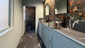 A modern bathroom with a marble floor, a vanity with a mirror, and a shower area. - Grand Théâtre view - Stylish 60m2 apartment (Bordeaux)