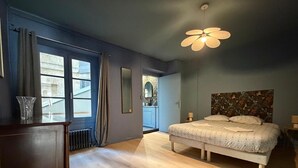 A bedroom with a bed, a dresser, a radiator, a window with curtains, and a ceiling fan. - Grand Théâtre view - Stylish 60m2 apartment (Bordeaux)