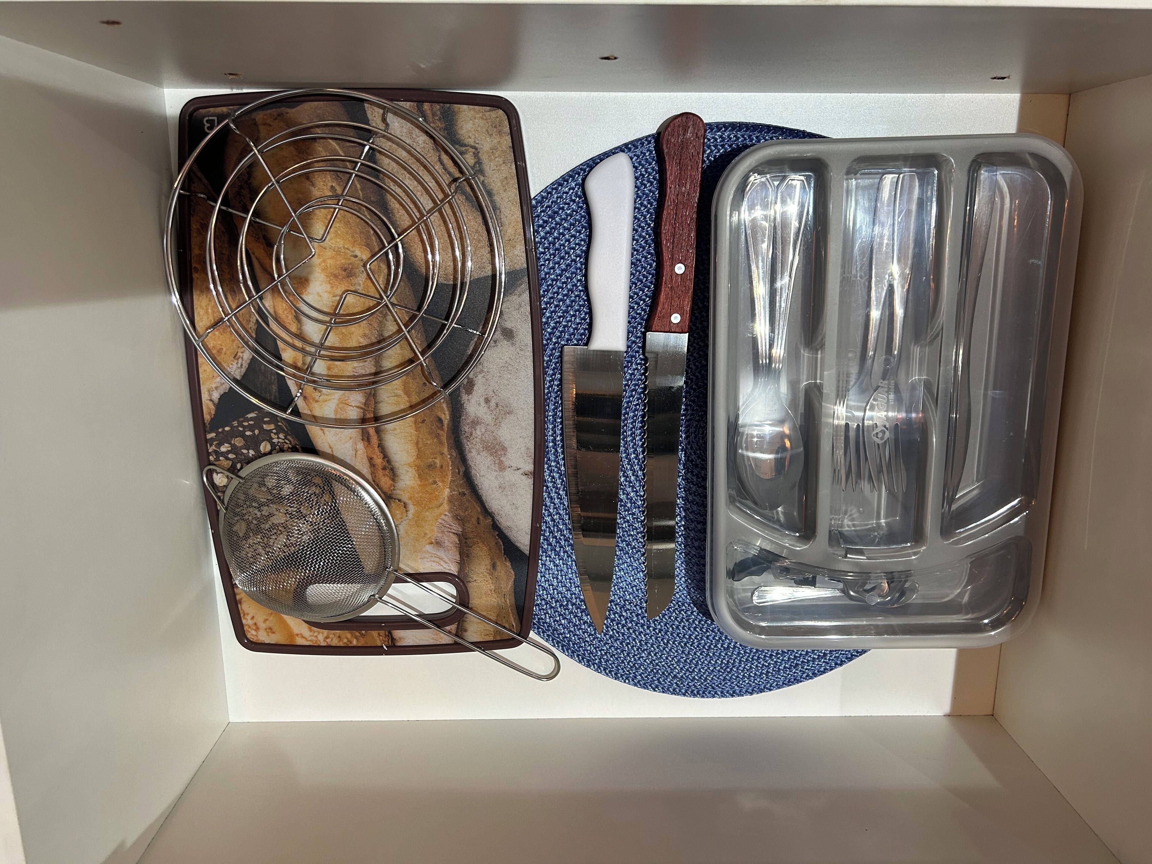 Una cocina con estufa, colador, cuchillo y bandeja para hornear.