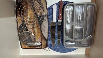 Una cocina con estufa, colador, cuchillo y bandeja para hornear.