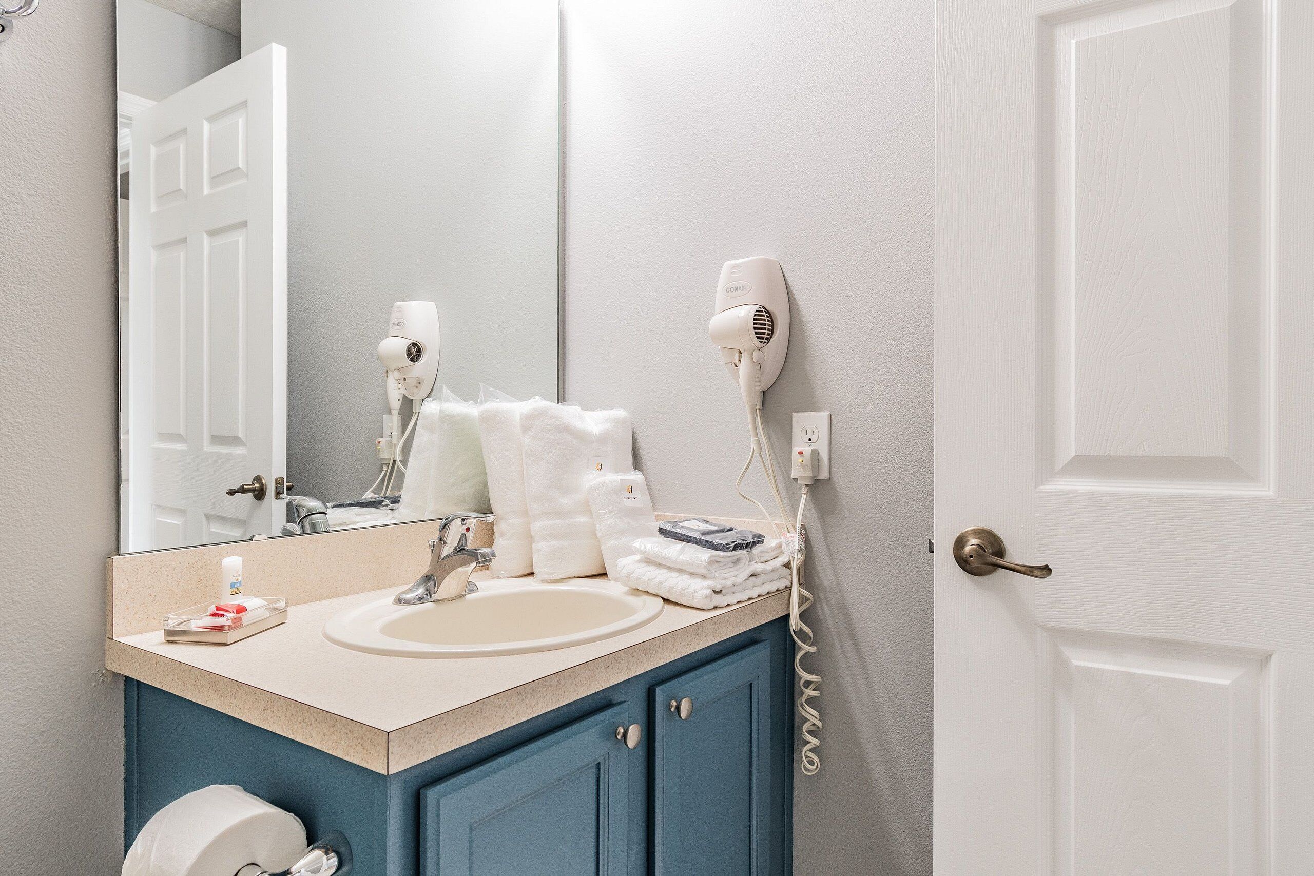 A bathroom with a sink, mirror, towel rack, and a hairdryer on the wall.