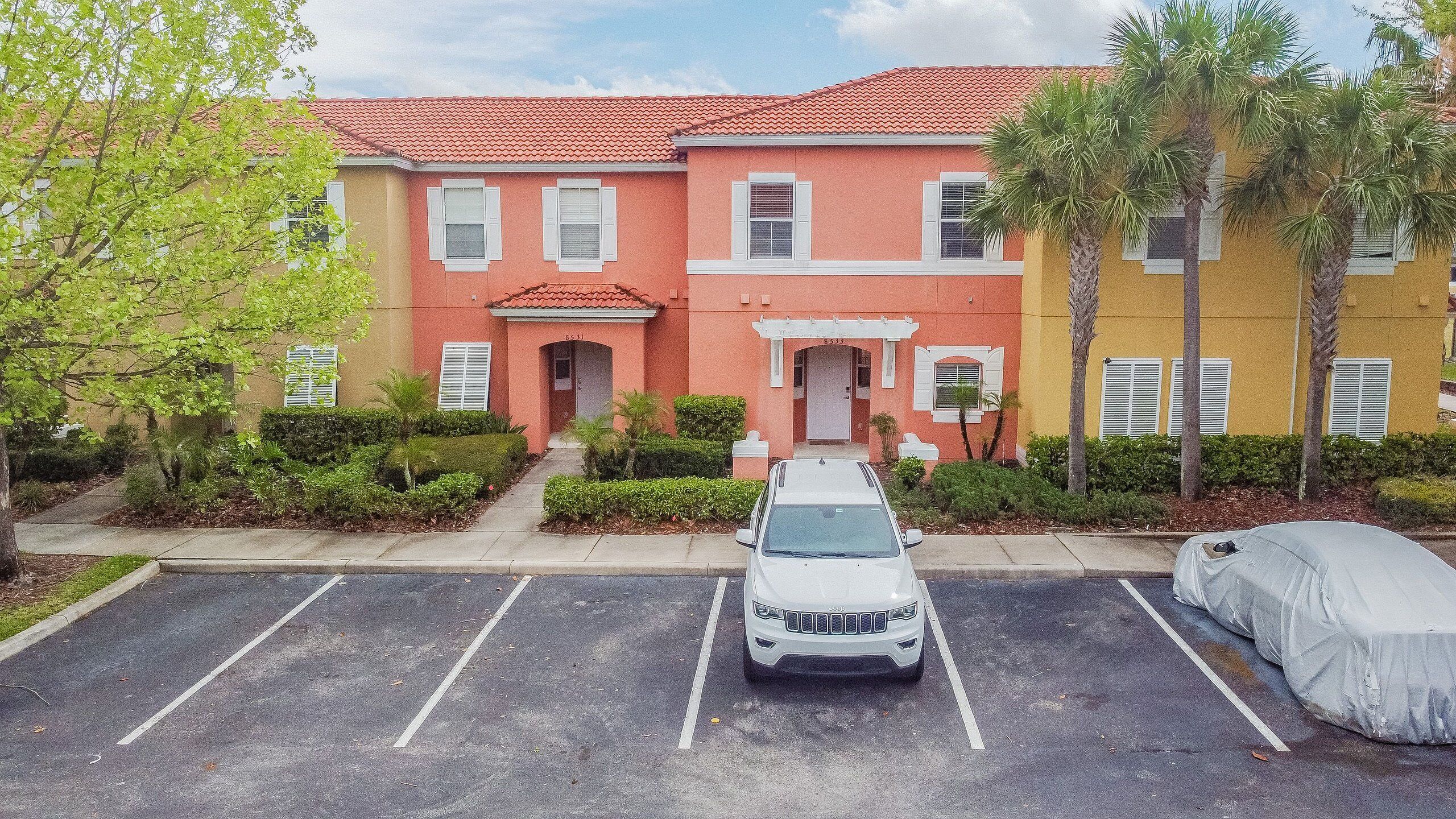 A multi-story residential building with a parking lot in front.