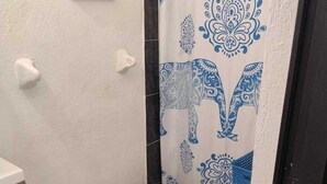 A small bathroom with a toilet, a shower curtain with a blue elephant pattern, a trash bin, and a framed sign on the wall. - Bungalow Turrent, 5 minutes from Playa Mocambo, Boca del Rio Veracruz (Veracruz)