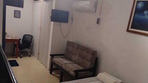A bedroom with a bed, a sofa, a desk with a chair, a TV, and an air conditioner. - Bungalow Turrent, 5 minutes from Playa Mocambo, Boca del Rio Veracruz (Veracruz)