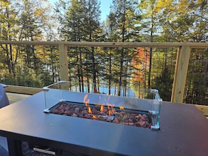 A barbecue grill on an outdoor table with a view of trees and a body of water.