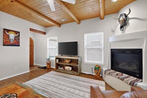 A living room with a fireplace, a television, and a rustic wooden ceiling.