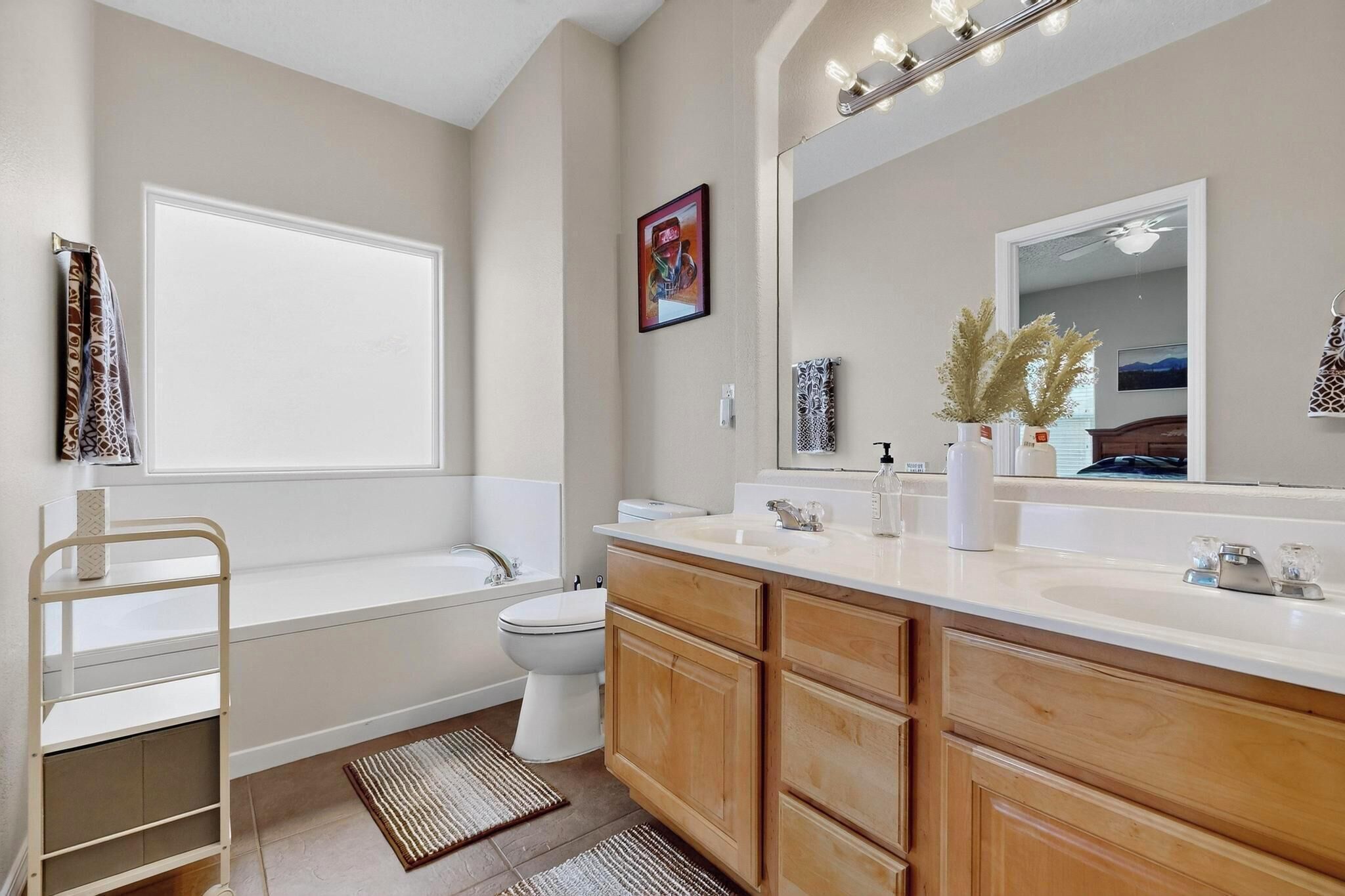 Un baño moderno con bañera, inodoro y tocador con un espejo grande.