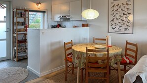 Una cocina acogedora con una mesa redonda, sillas de madera y una lámpara colgante.