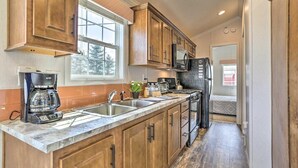A kitchen with wooden cabinets, a built-in microwave, and a coffee maker. - NYC Escape | Pocono Cabin & Suite (Pleasant Mount)