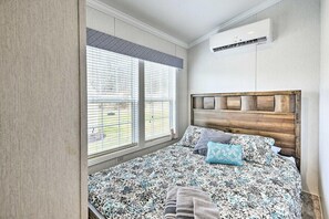 A bedroom with a bed, window blinds, an air conditioning unit, and a wooden headboard. - Romance & Relaxation in a Luxury Mountain Stay (Pleasant Mount)