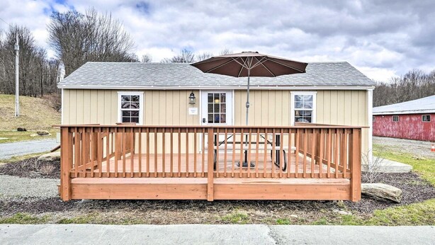 A single-story building with a wooden deck, a covered patio area, and a red barn in the background. - Fresh Air and Pet Friendly · Poconos Haven (Pleasant Mount)