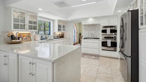 A modern kitchen with white cabinetry, a large island, and built-in appliances. - La Encantada Luxe Desert Retreat (Tucson)